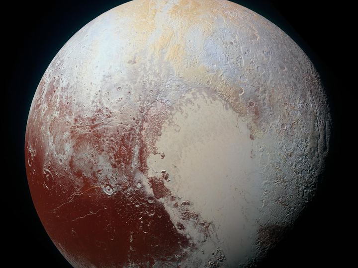 Pluto in enhanced color, with a pale heart-shaped plain surrounded by tan, red and blue-gray terrain